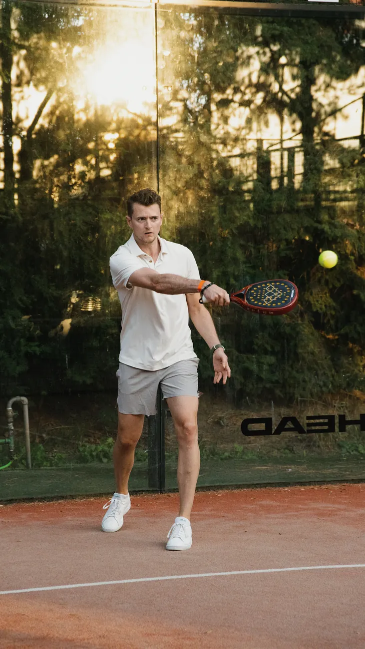 Padel player hitting the ball in the evening light